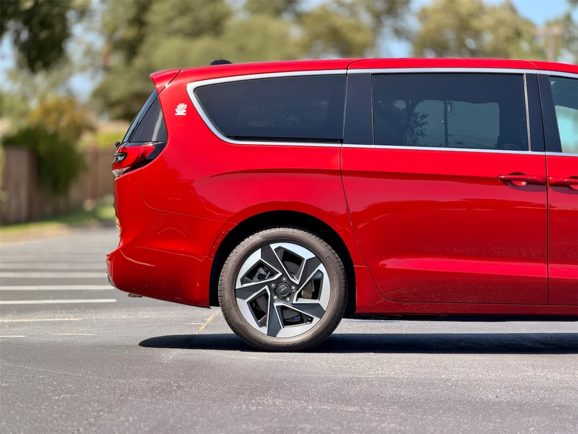Side profile of a red 2027 Chrysler Pacifica in a neighborhood