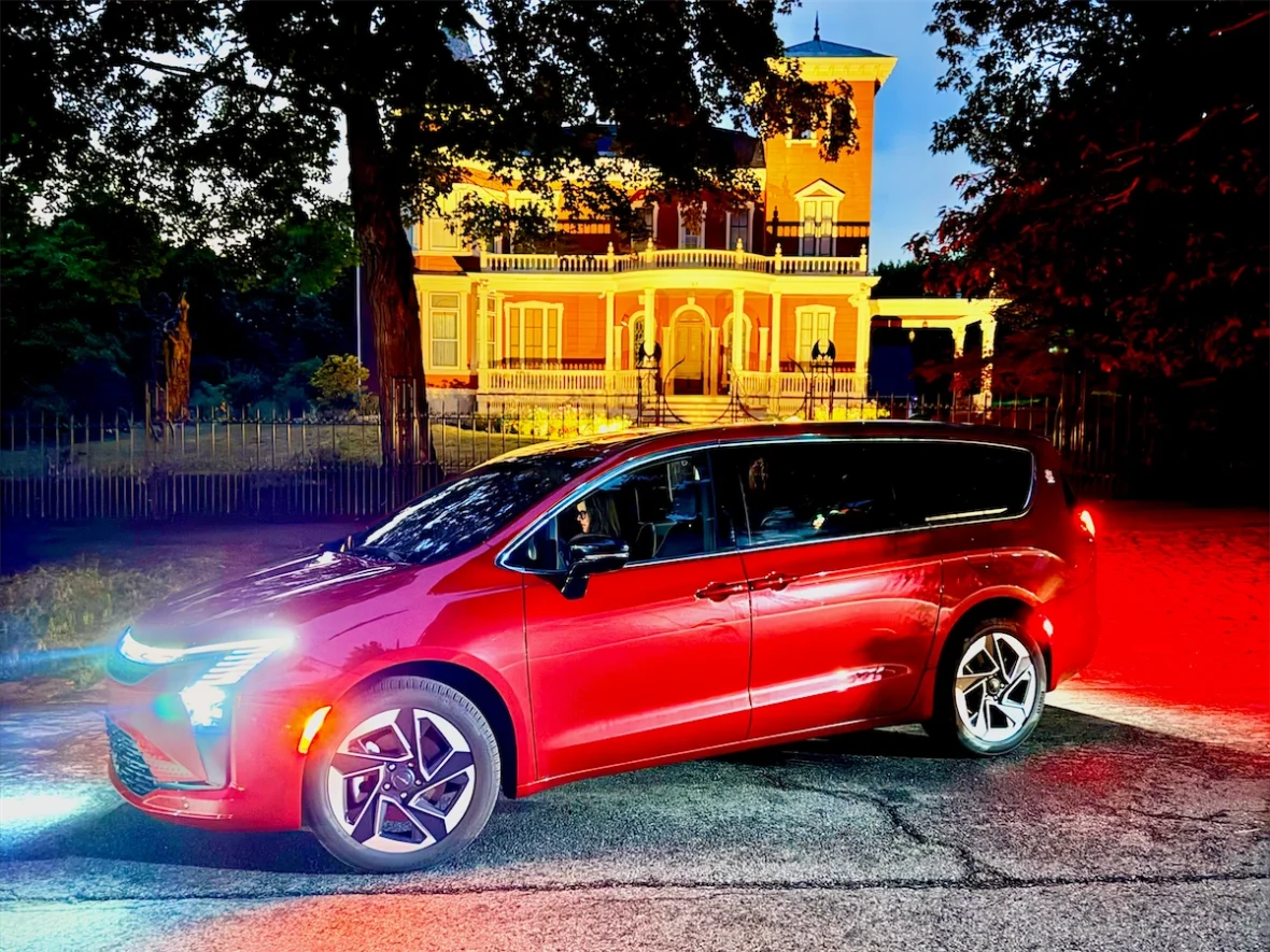 Red 2027 Chrysler Pacifica at night in front of Stephen King's Victorian mansion in Bangor, Maine