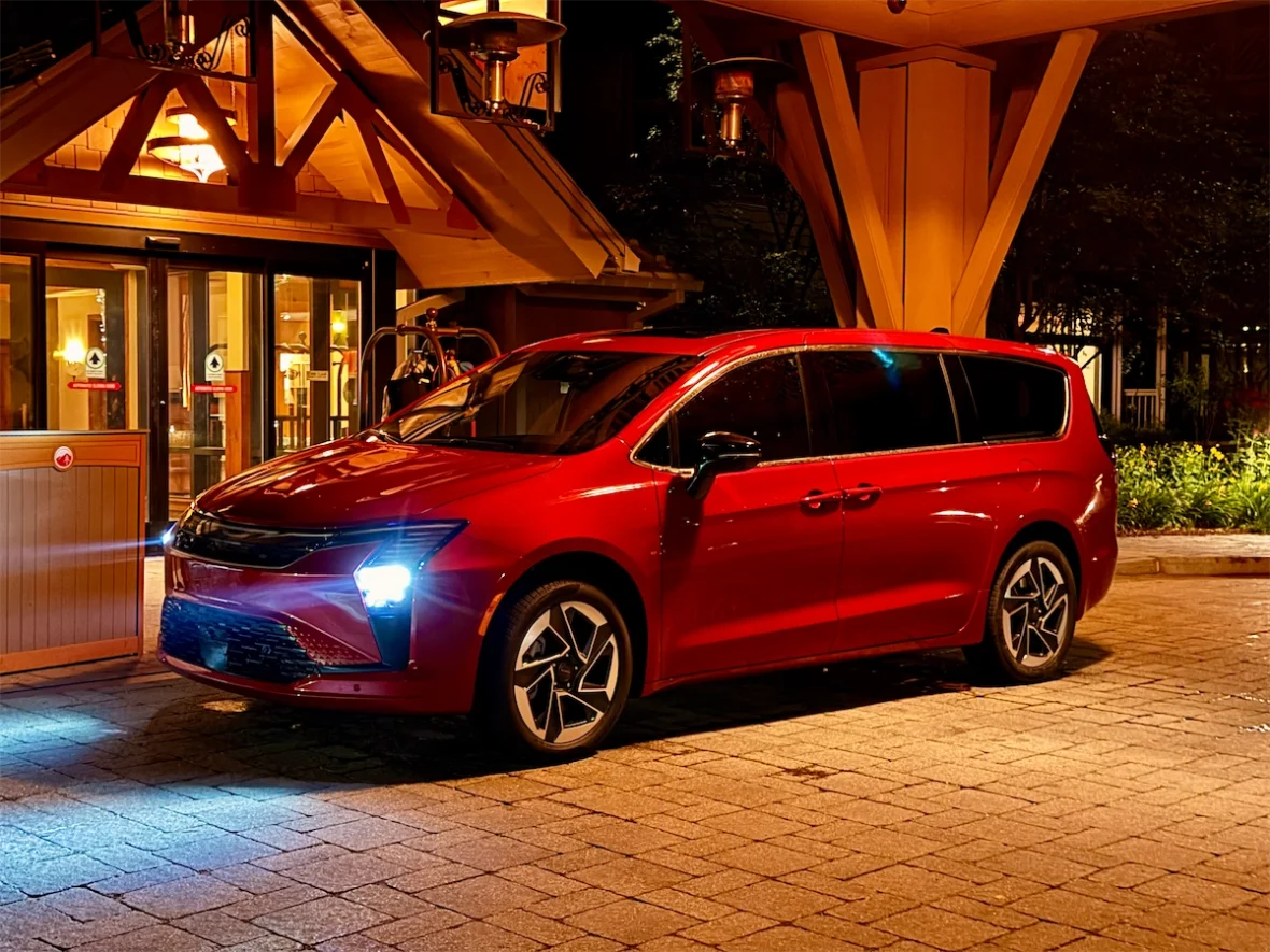 Red 2027 Chrysler Pacifica Limited AWD at night under a timber lodge entrance in Stowe, Vermont