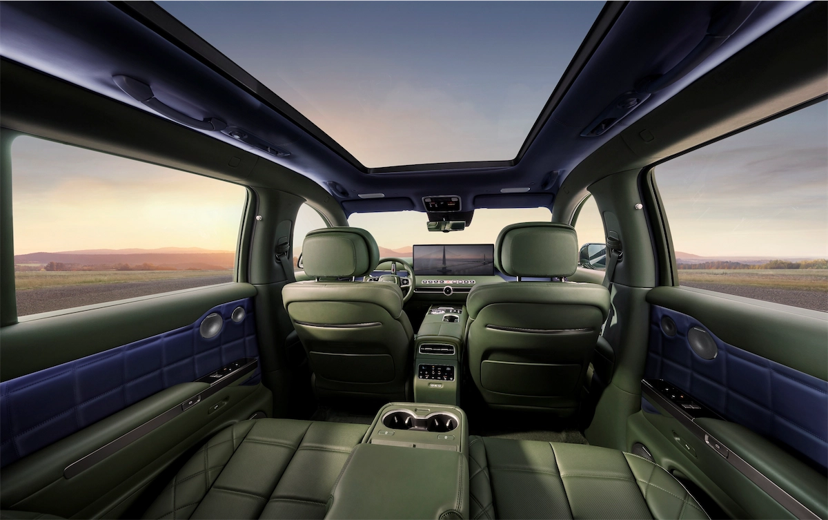 View from the back of a luxury SUV cabin toward the dashboard under a full-length glass roof