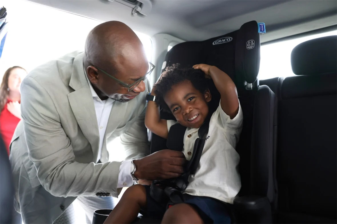 Parent tightening a child’s harness for a snug, correct fit