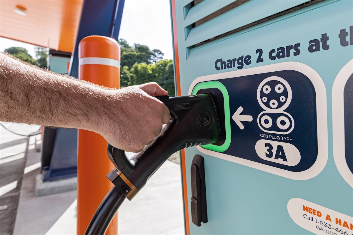 Close-up of a driver plugging a CCS connector into an EV