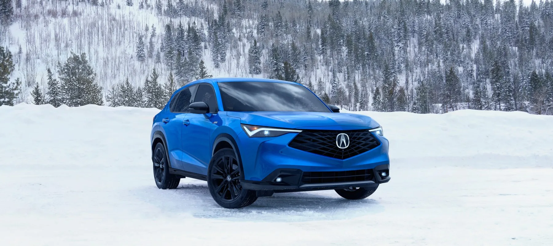 Blue Acura ADX parked on a snowy mountain road