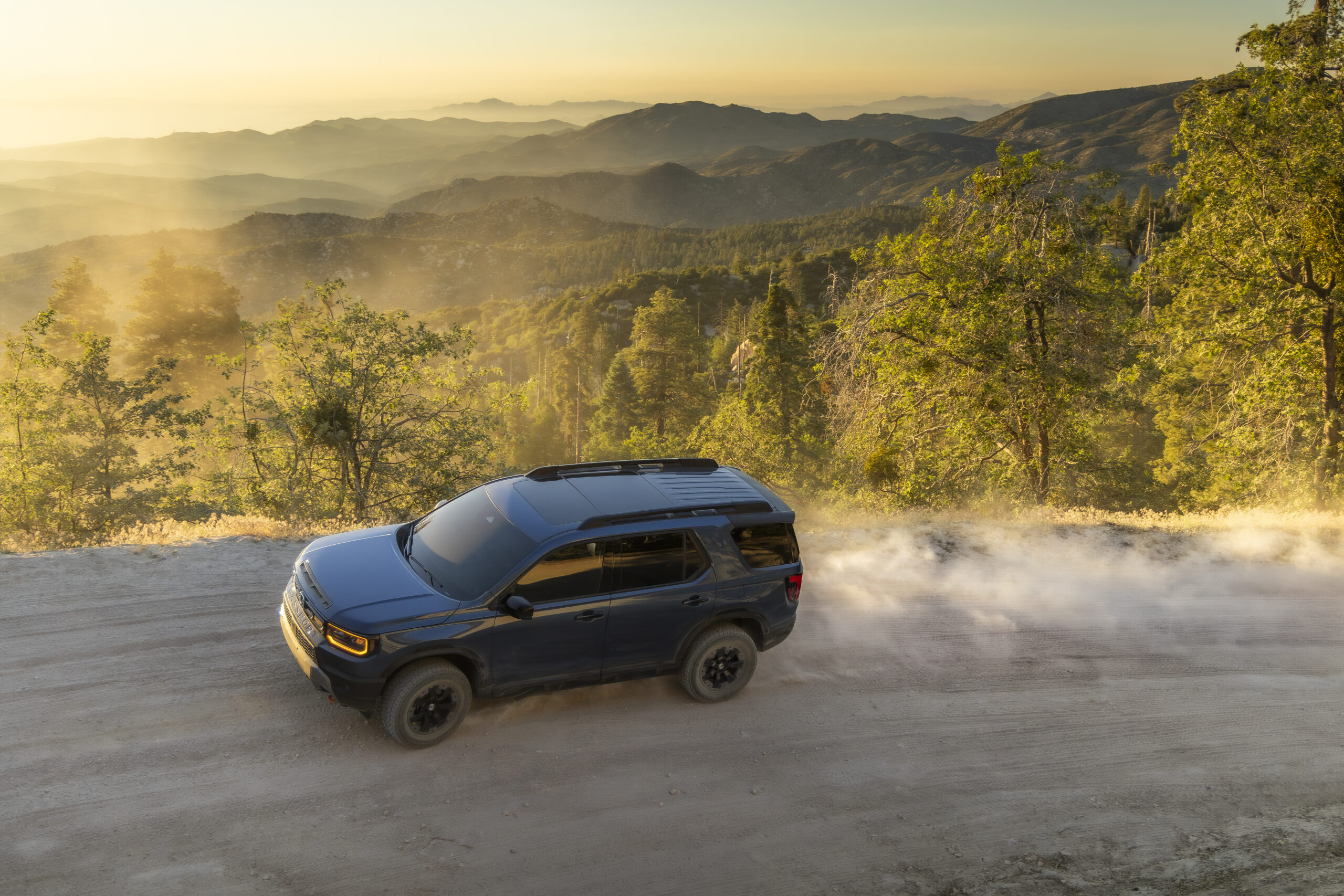 2027 Honda Passport TrailSport driving on a mountain road at sunset