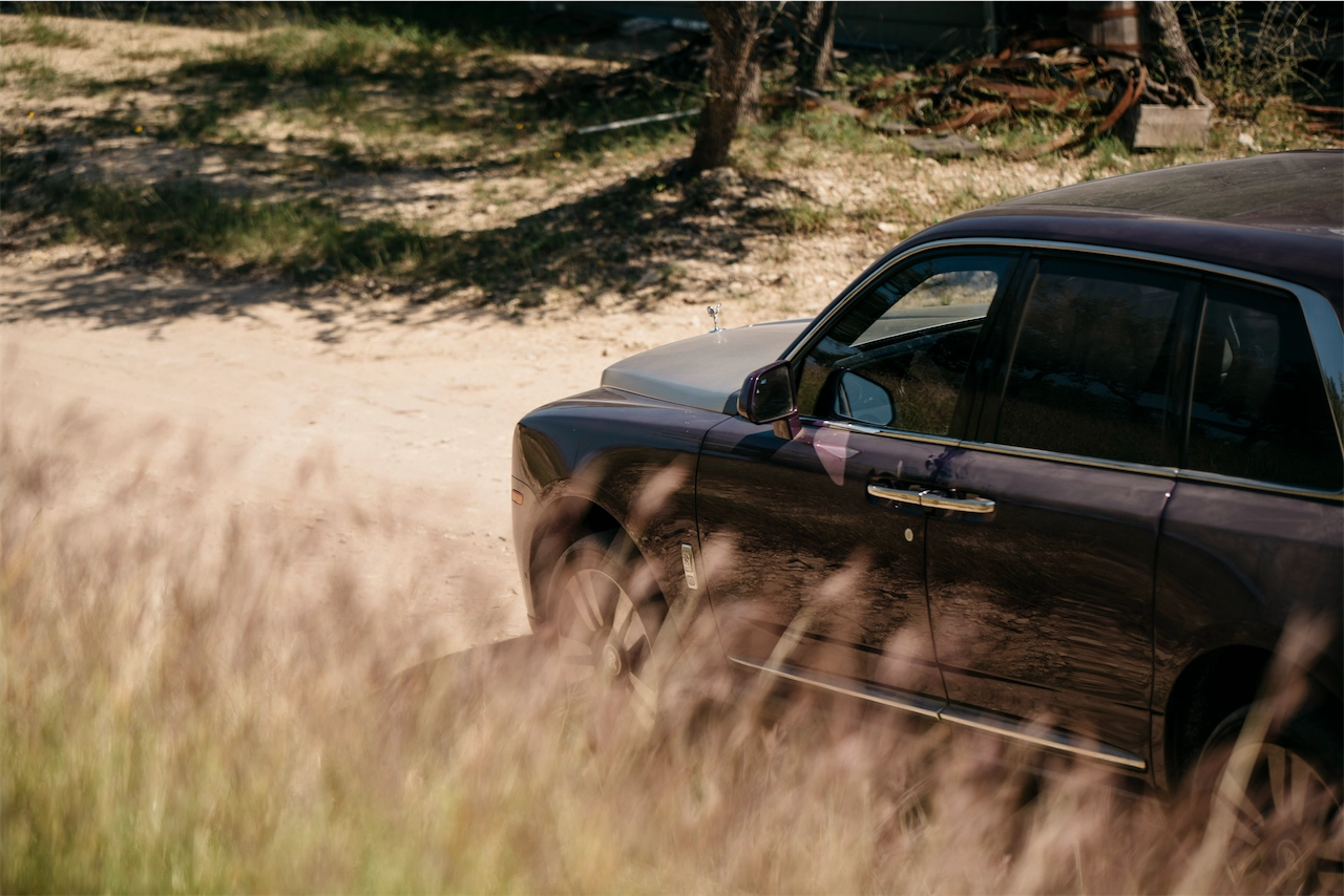 Rolls-Royce Cullinan driving through tall Texas grass