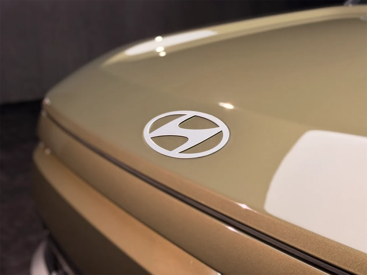 Close-up of a Hyundai logo on a beige car hood.