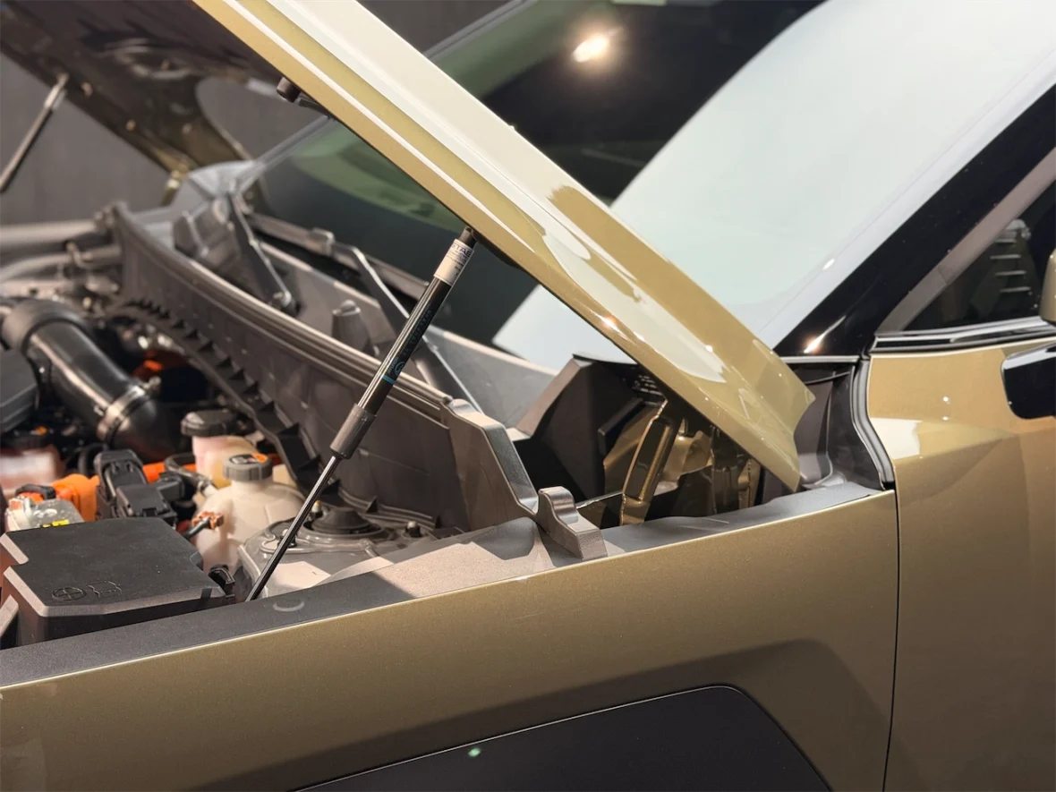 Close-up view of a car engine with the hood raised, showcasing the engine components and support strut.
