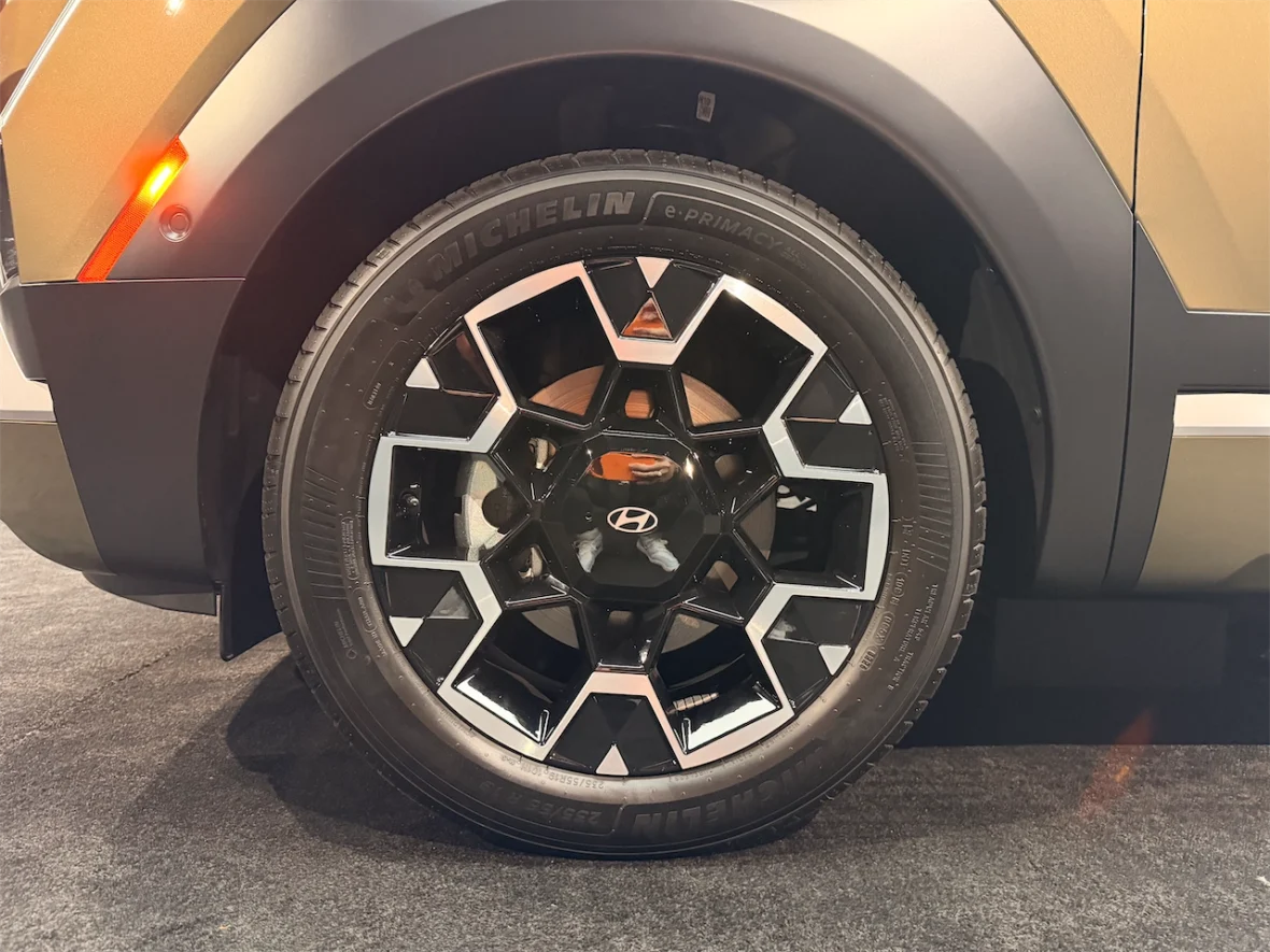 Close-up view of a stylish black and silver alloy wheel on a vehicle, featuring a unique geometric design and a Michelin tire.