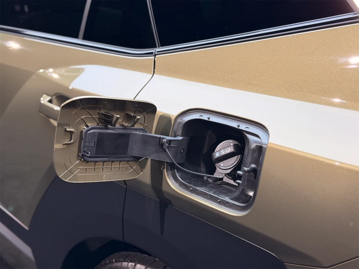 Close-up of a car's fuel cap, showing the opened fuel door and gas cap.