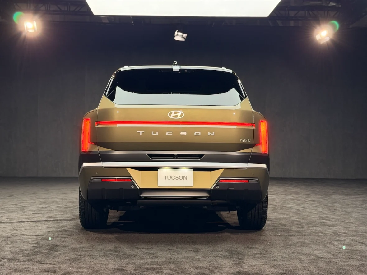 Rear view of a Hyundai Tucson hybrid SUV on a dark stage with spotlight lighting.