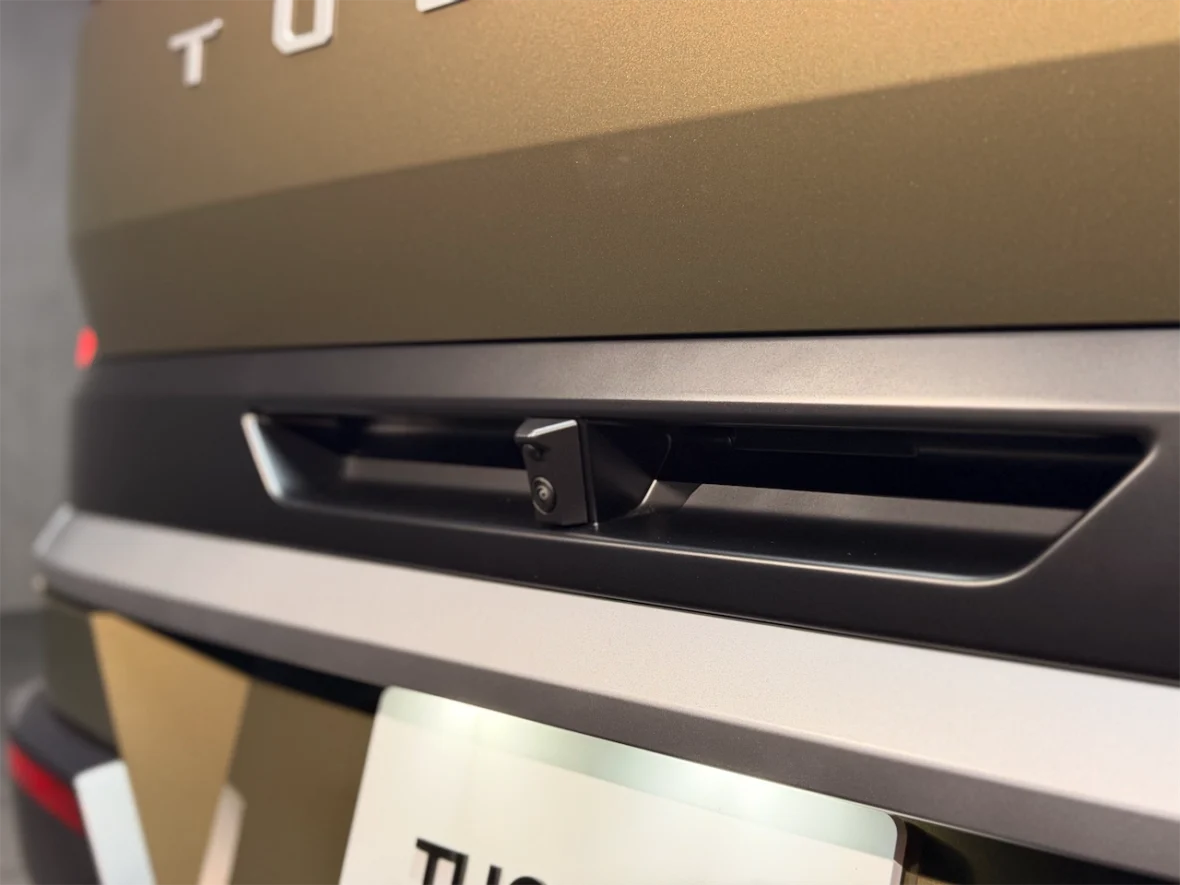 Close-up of a rear camera integrated into the tailgate of a vehicle with a matte finish.