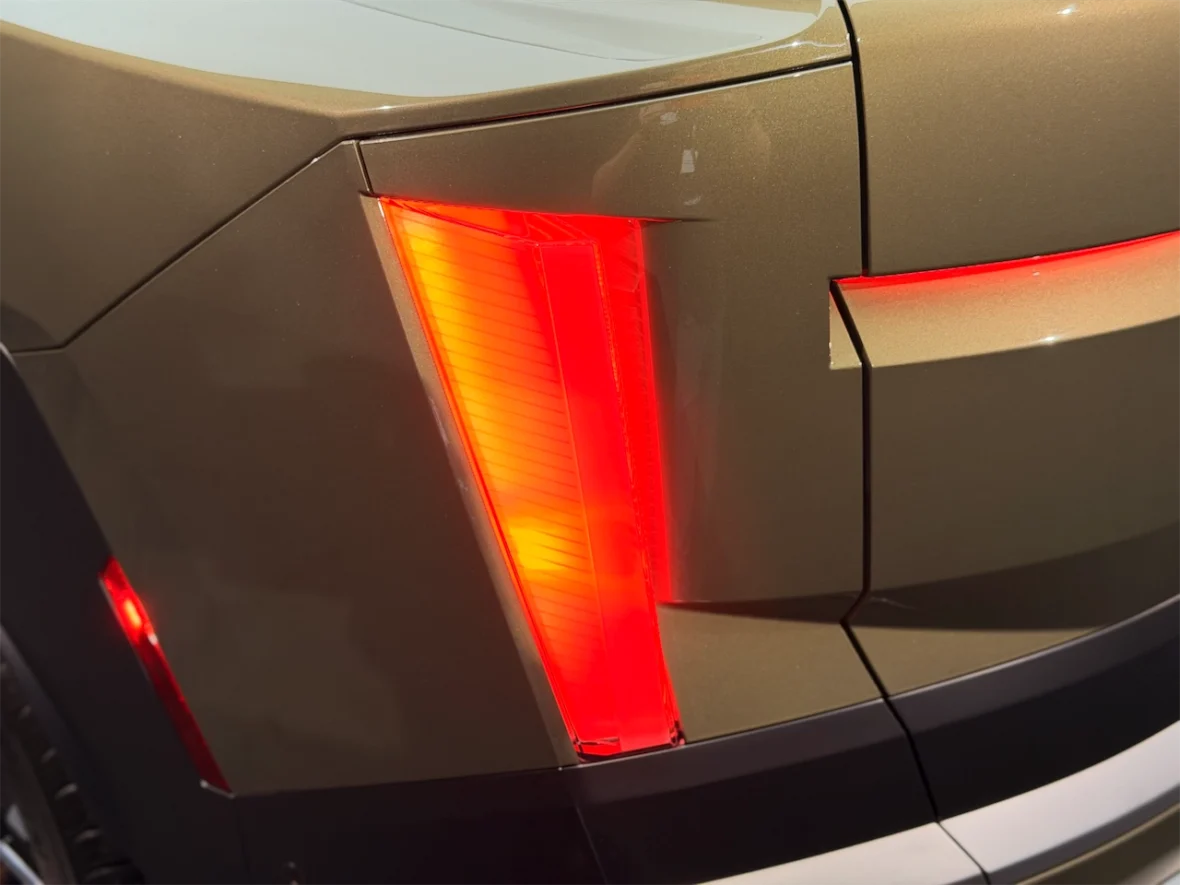 Close-up of a car's rear taillight in bright red, set against a gold-colored surface.