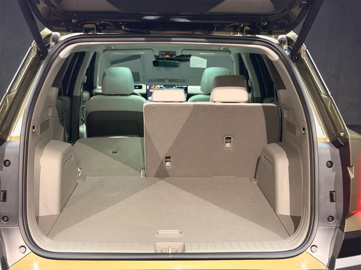 Interior view of an SUV's cargo space with rear seats folded down, showcasing a spacious gray carpeted area.