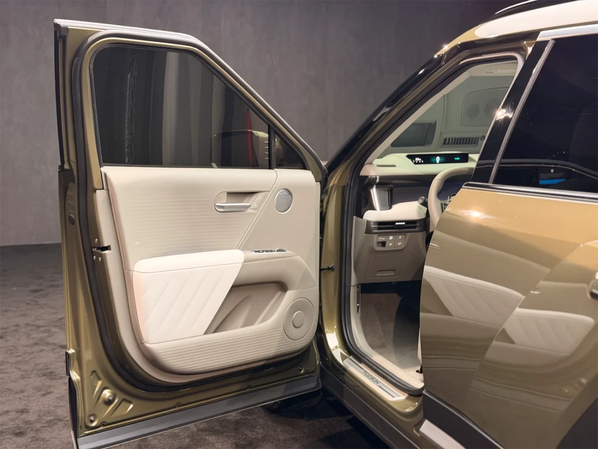 Interior view of a car door open, showcasing a beige and white upholstery design and modern dashboard elements.