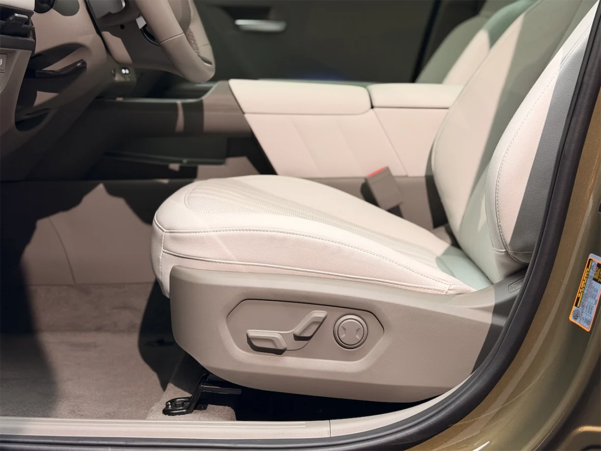 Interior view of a car showing a white leather driver's seat with adjustable controls on the side.