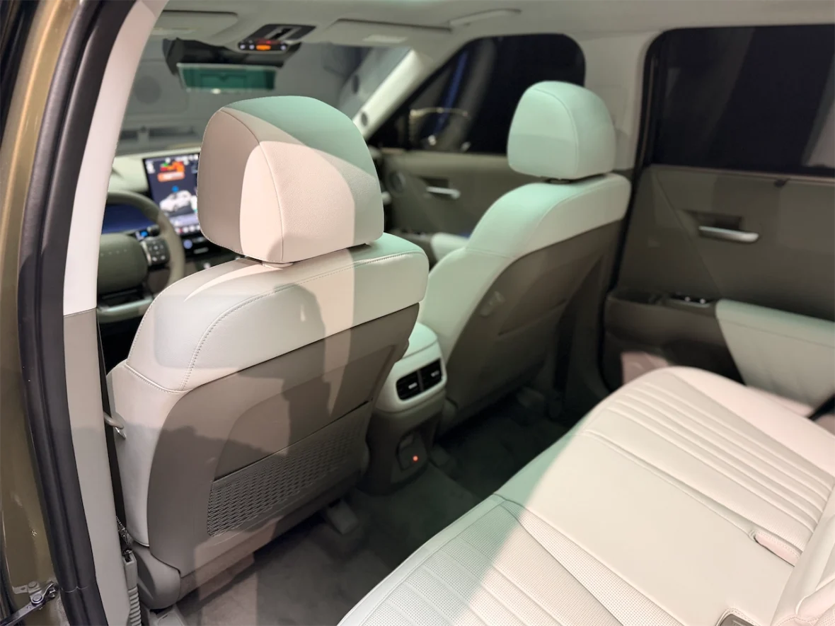 Interior view of a vehicle showcasing the back seats with light-colored upholstery and a dashboard in the background.