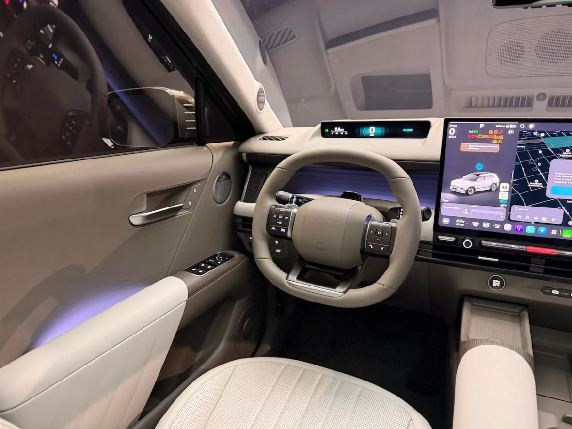 Interior view of a modern car showcasing a sleek steering wheel, digital dashboard display, and touchscreen interface with navigation and vehicle controls.