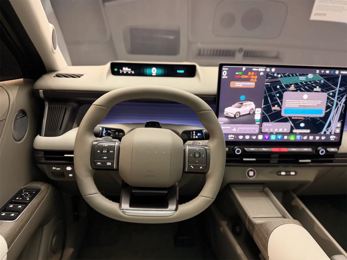 Interior view of a modern car dashboard and steering wheel, featuring a digital display with navigation and user interface controls.