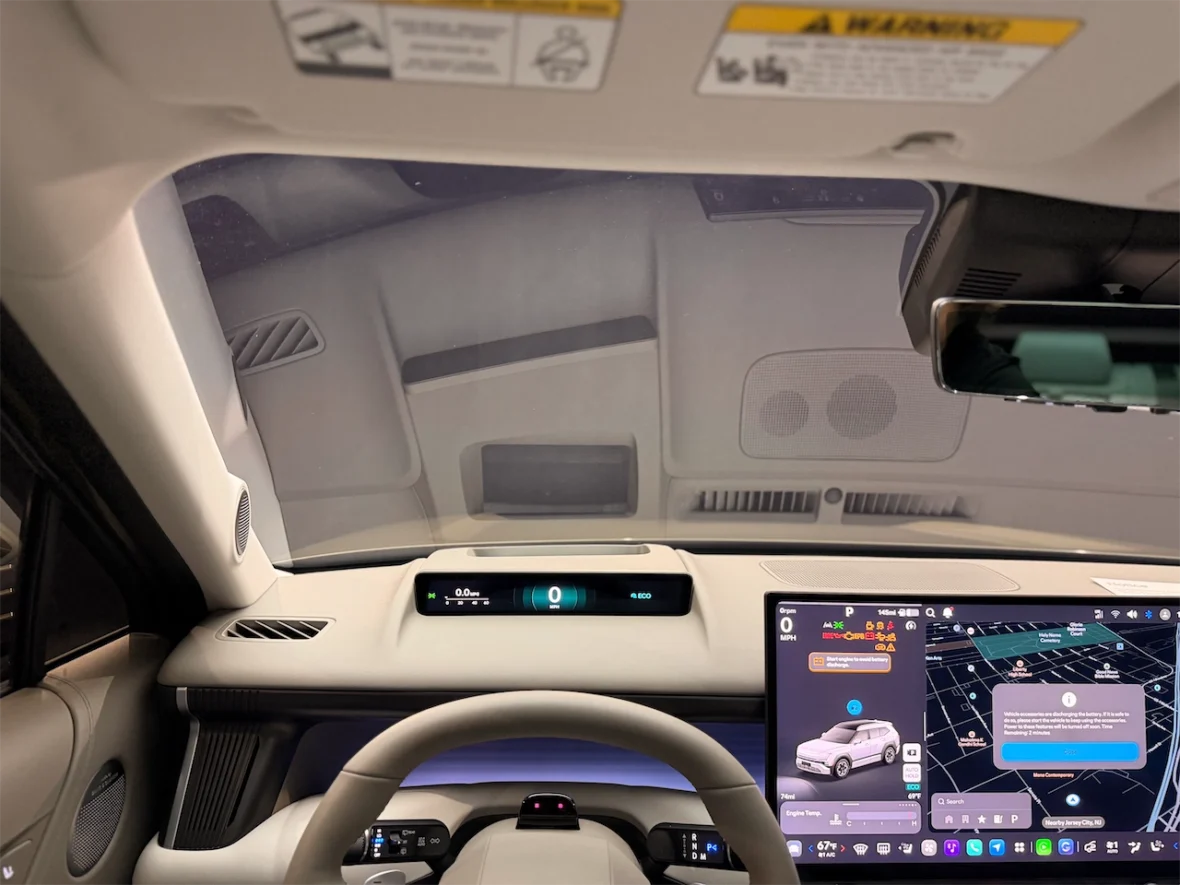 Interior view of a modern car dashboard showing the steering wheel, digital speedometer displaying 0 MPH, and a touchscreen navigation system with a map and vehicle information.