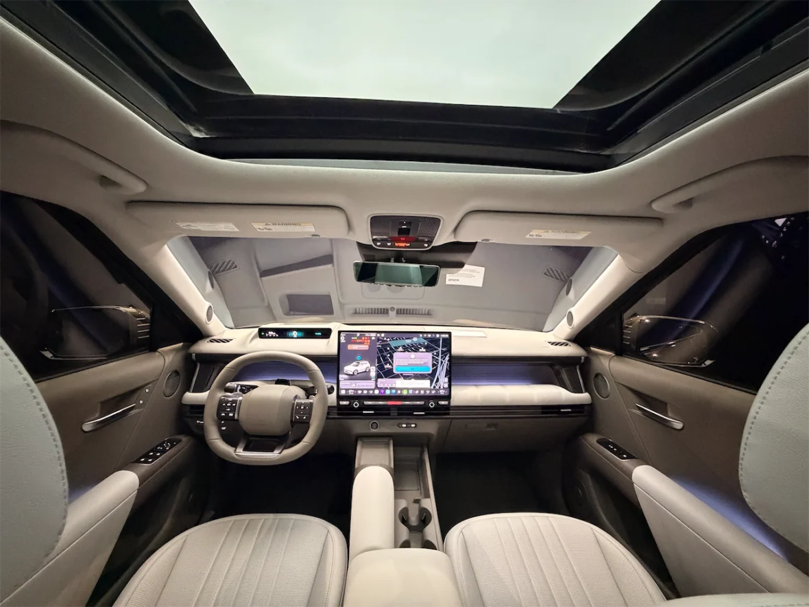 Interior view of a modern car showcasing a large touchscreen display, a steering wheel, and a panoramic sunroof.