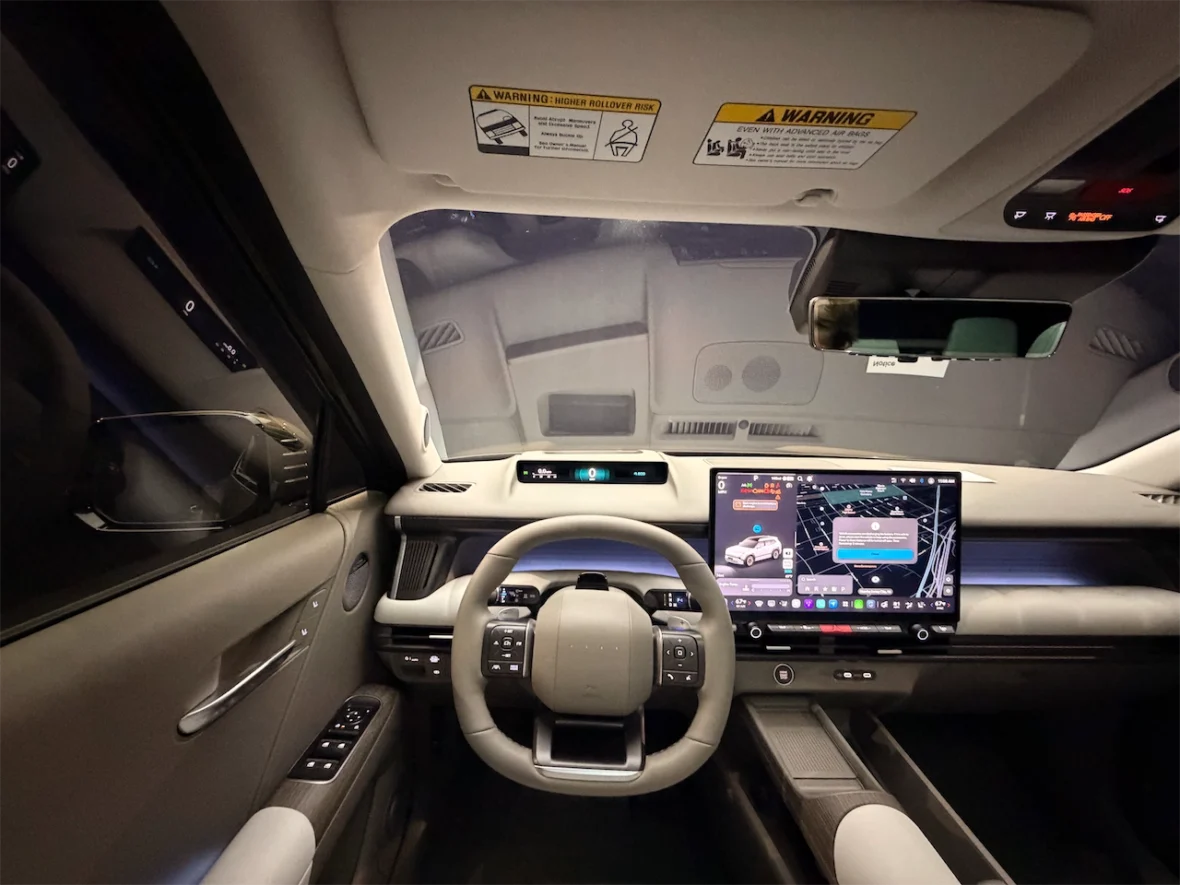 Interior view of a modern car dashboard featuring a steering wheel and a large touchscreen display with navigation and control options.