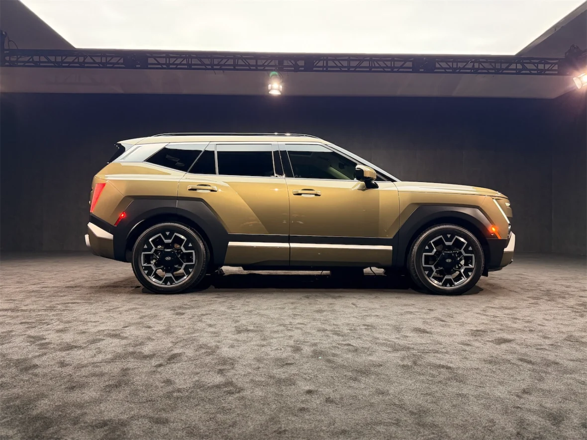 Side view of a modern SUV in a sleek exhibition setting, showcasing its angular design and stylish alloy wheels.
