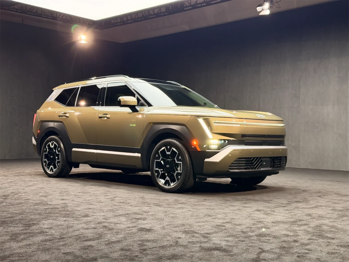 A modern SUV with a distinctive design, featuring a sleek gold exterior and black accents, displayed in a well-lit studio environment.