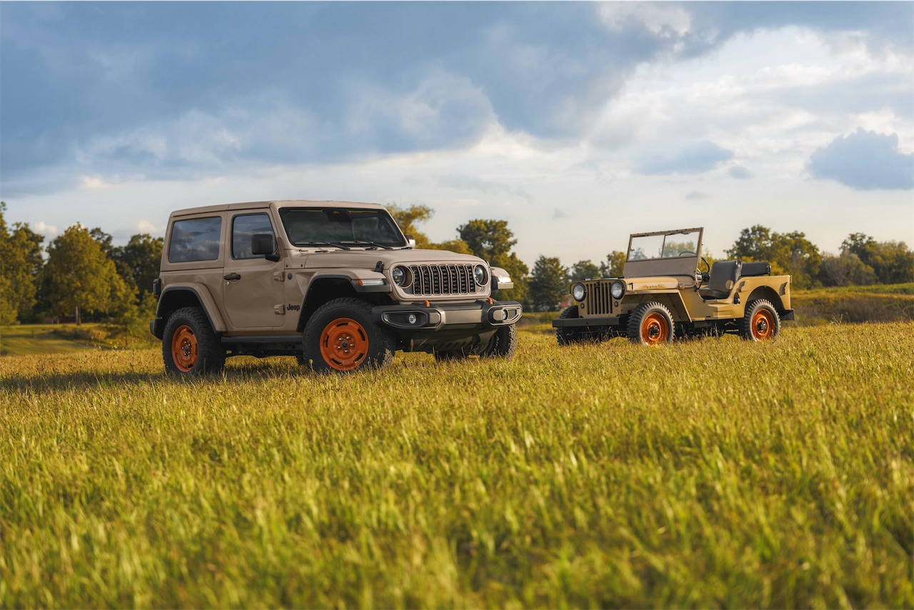 2027 Jeep Wrangler JL-2A parked beside a vintage Willys CJ-2A in a field