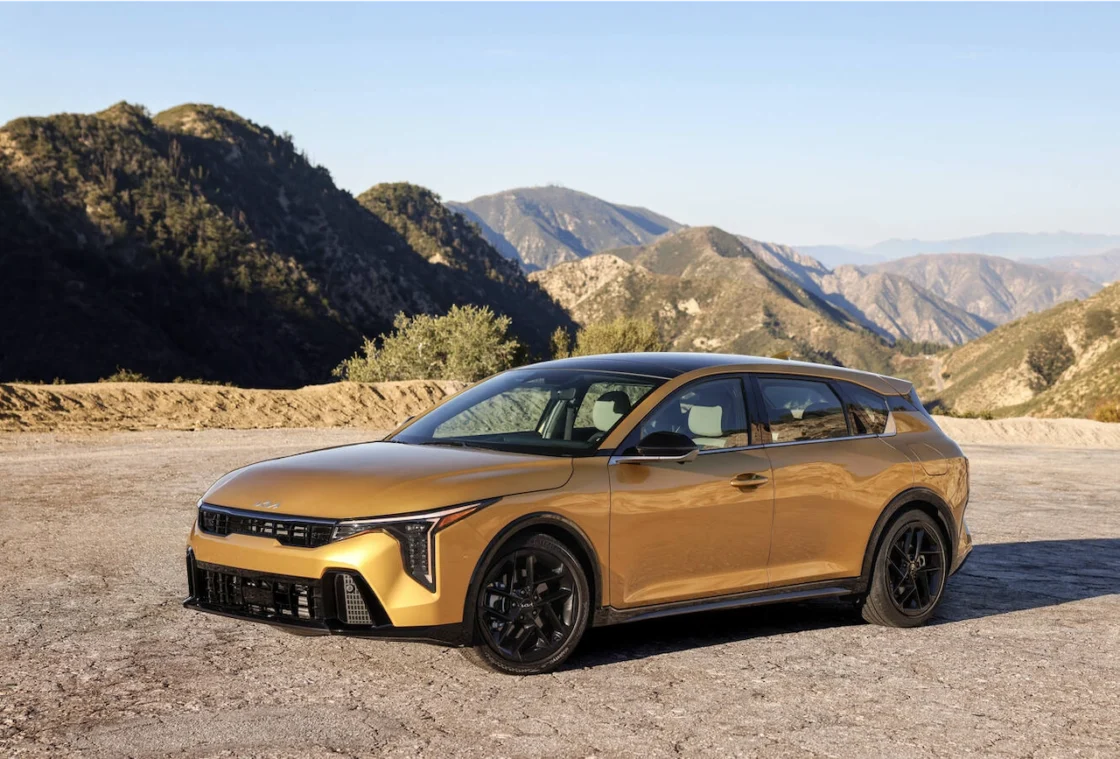 Gold Kia K4 hatchback on a mountain road