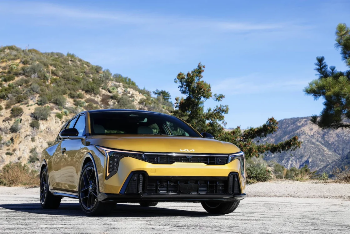 Front view of a gold Kia K4 hatchback on a hillside road