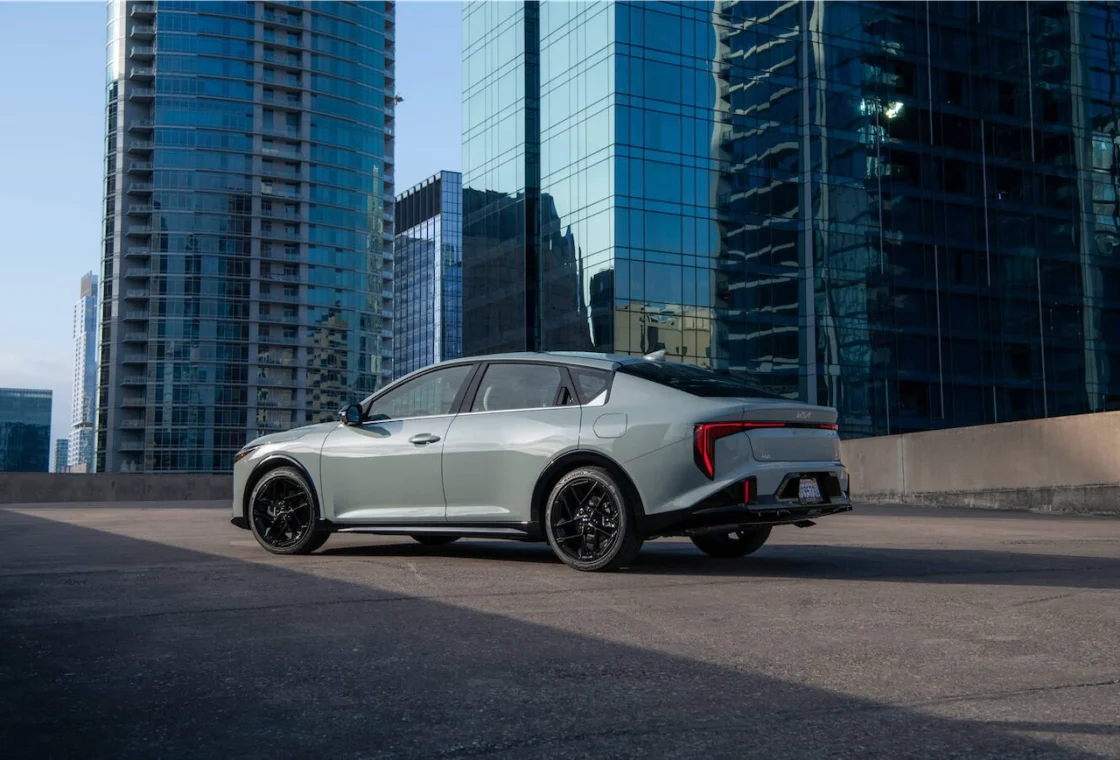 2027 Kia K4 sedan parked on a rooftop among city towers