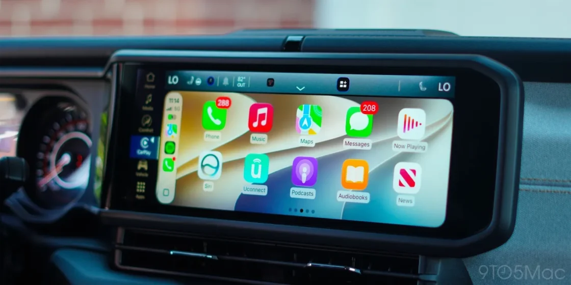 iOS 27 CarPlay home screen with Liquid Glass app icons on a vehicle's widescreen dashboard display