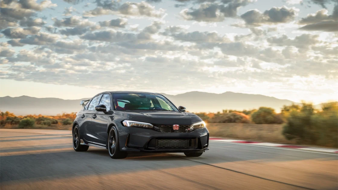 Dark gray 2027 Honda Civic Type R on a racetrack at sunset with mountains behind it