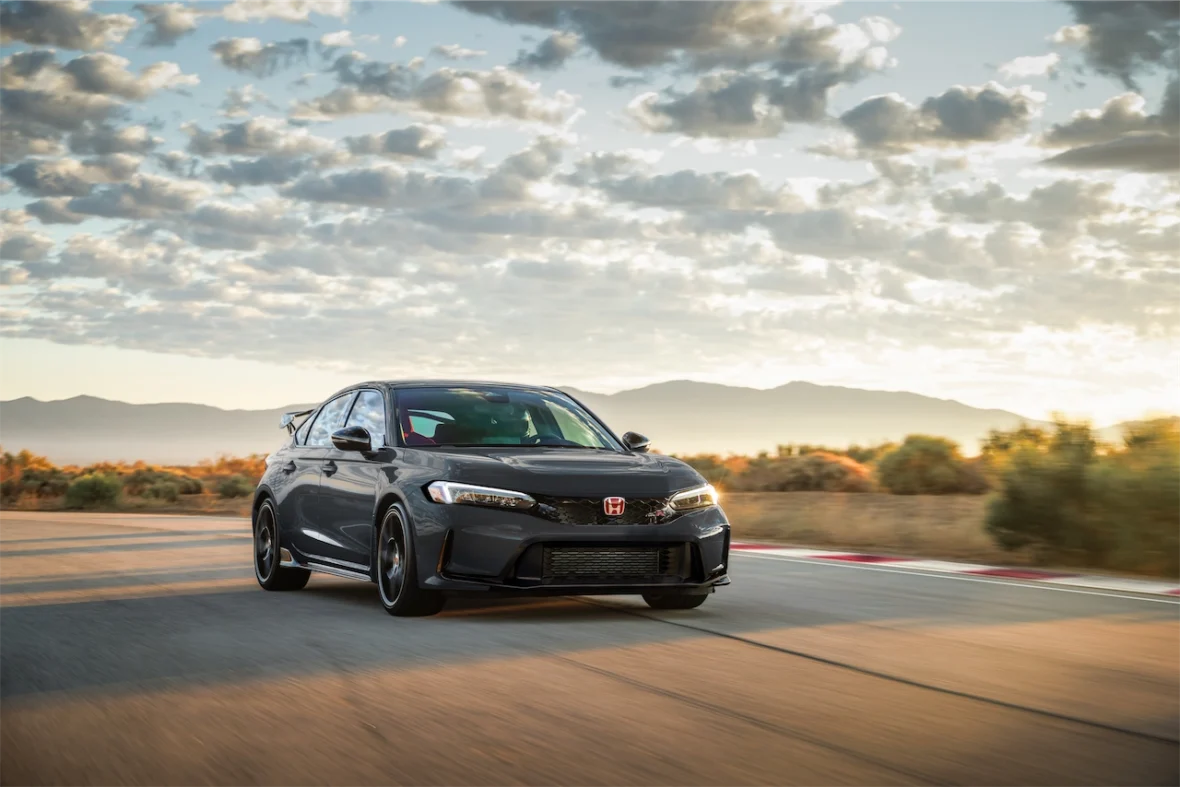 Dark gray 2027 Honda Civic Type R on a racetrack at sunset with mountains behind it