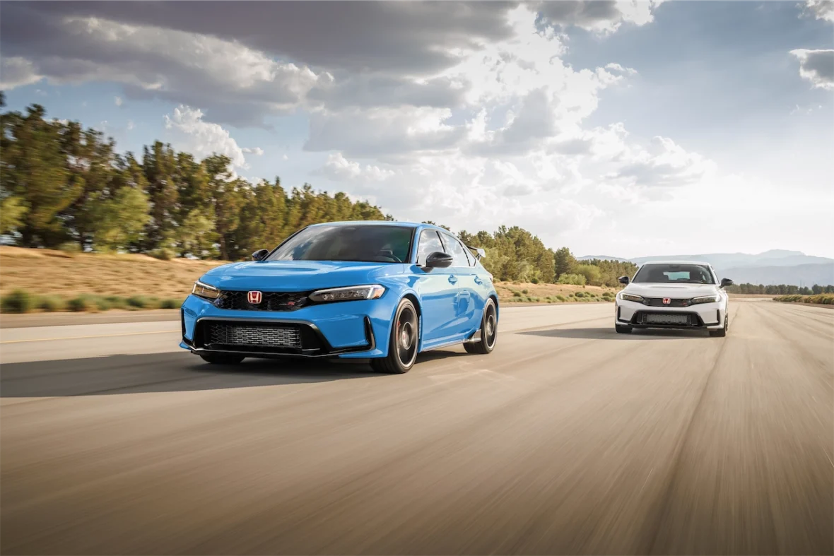 Boost Blue Pearl and Championship White 2027 Honda Civic Type R models driving side by side on a tree-lined road