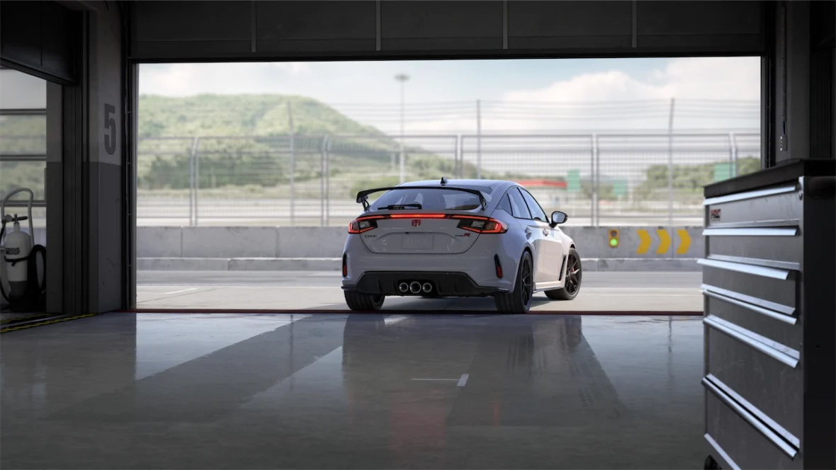 Sonic Gray Pearl Civic Type R pulling out of a pit garage toward green hills