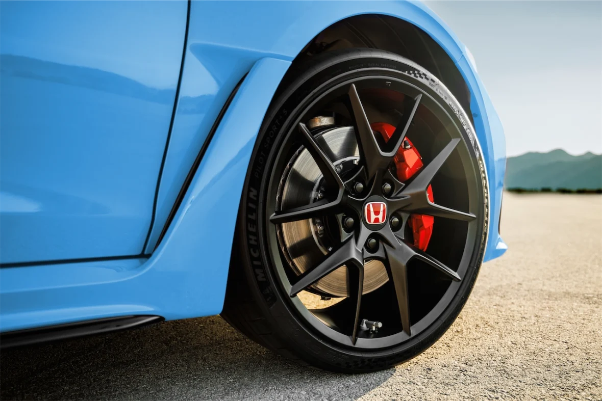 Close-up of a black wheel and red brake caliper on a Boost Blue Pearl Civic Type R