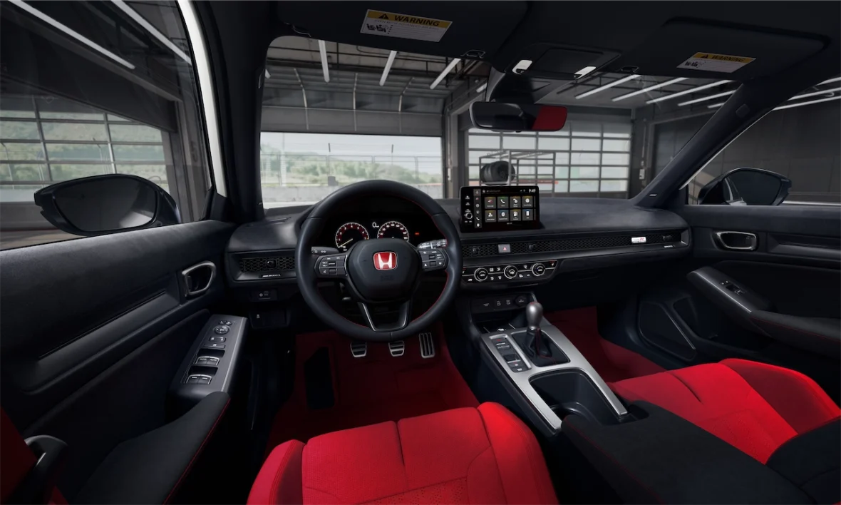 Civic Type R cockpit with a red Honda badge on the steering wheel, red seats, and digital gauges