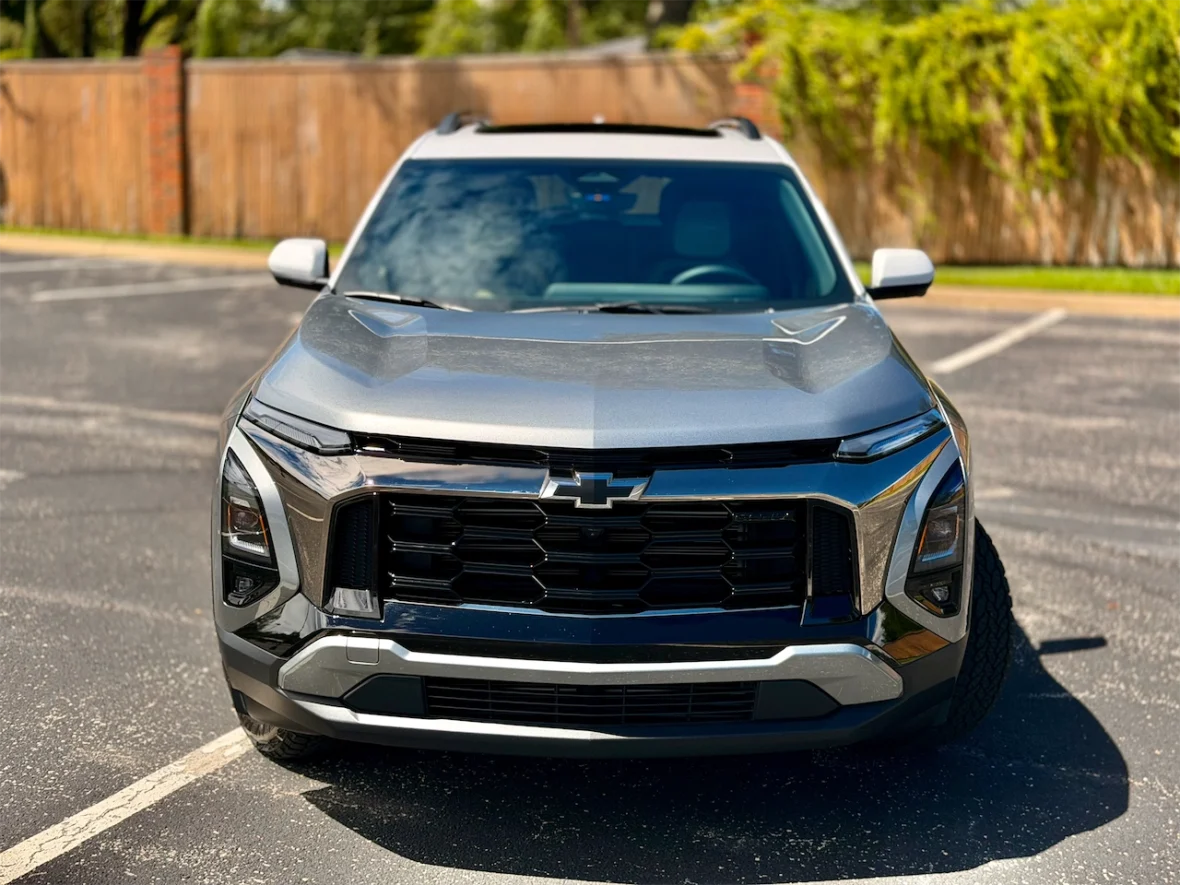 Front view of a gray Chevrolet SUV parked on an asphalt surface with a wooden fence in the background.