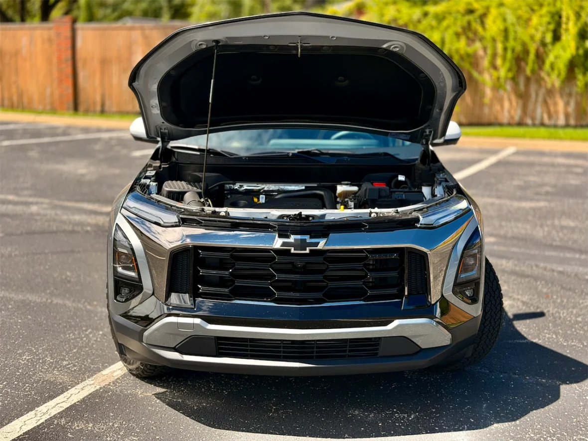 Front view of a Chevrolet vehicle with the hood open, showcasing the engine compartment, parked on an asphalt surface.