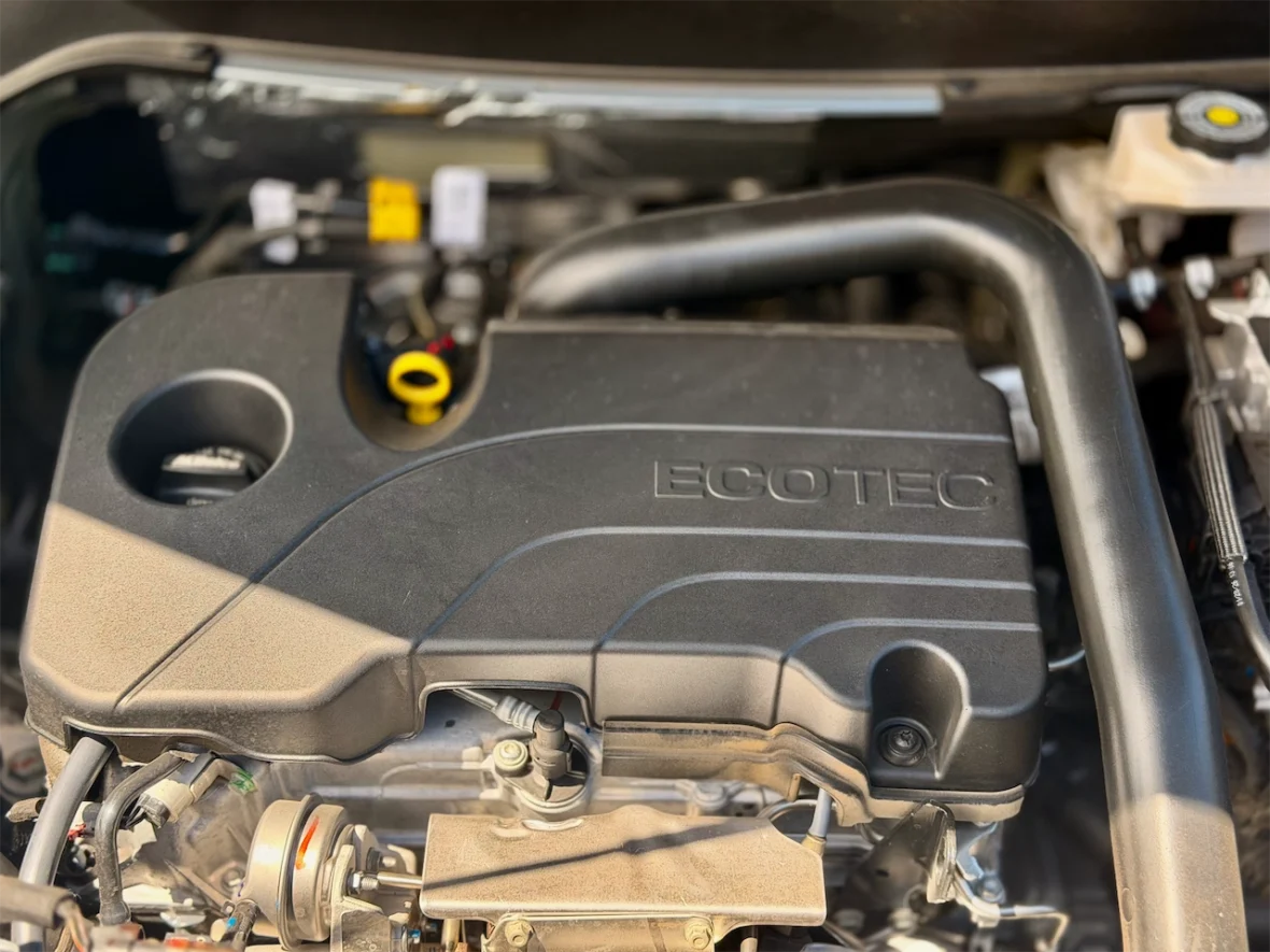 Close-up view of an Ecotec engine cover with various components visible beneath it.
