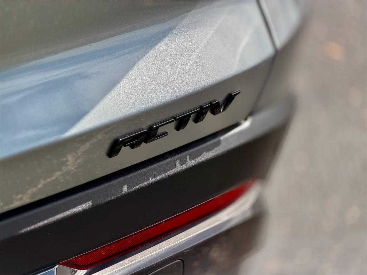 Close-up of a car's rear emblem displaying the letters 'ACTIV' in black against a metallic gray background.