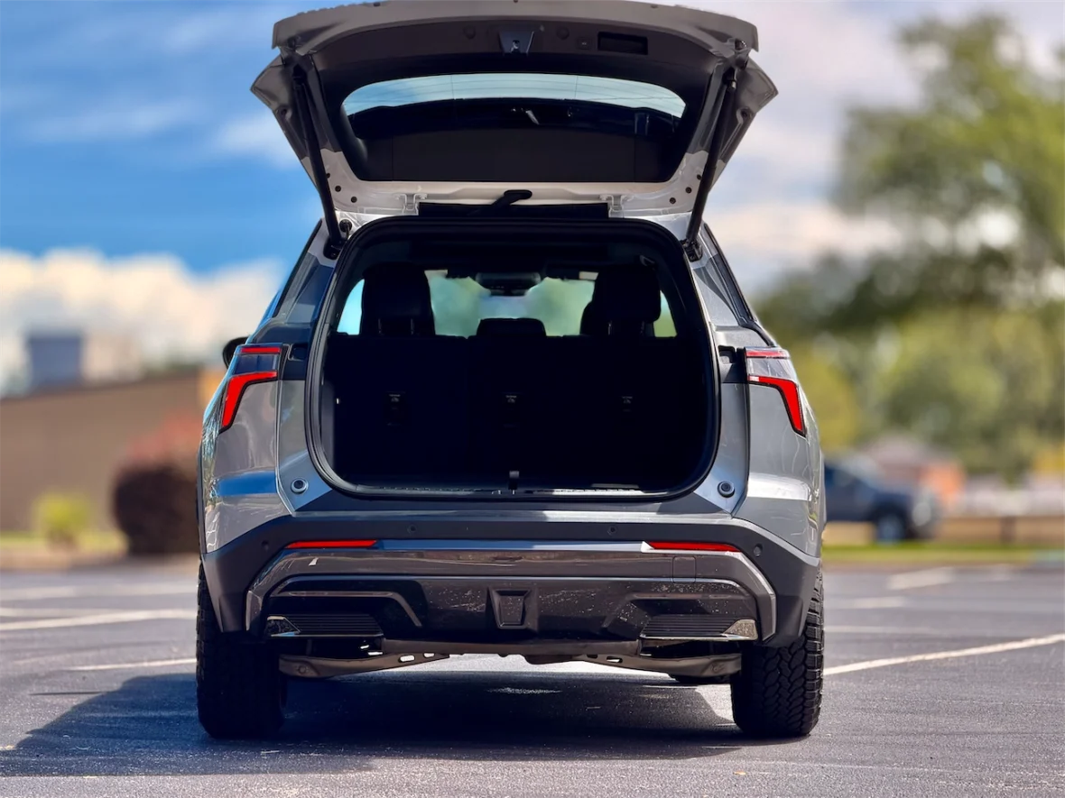 A silver SUV with an open rear hatch, showcasing the empty cargo space inside, parked on a sunny outdoor lot.