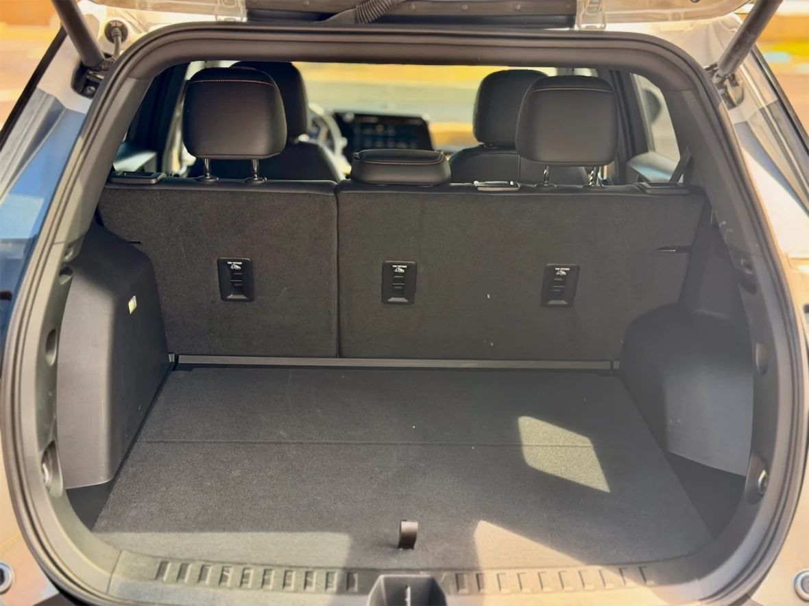 Interior view of a car trunk with two rear seats visible, featuring a flat cargo space and side storage compartments.