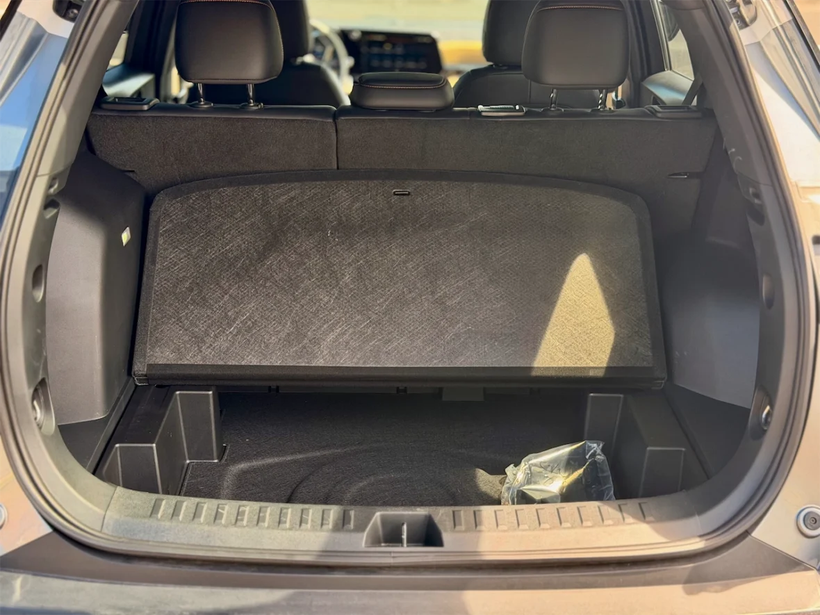 Interior view of a car trunk showcasing a spacious area with a foldable cargo cover and dark carpeting.