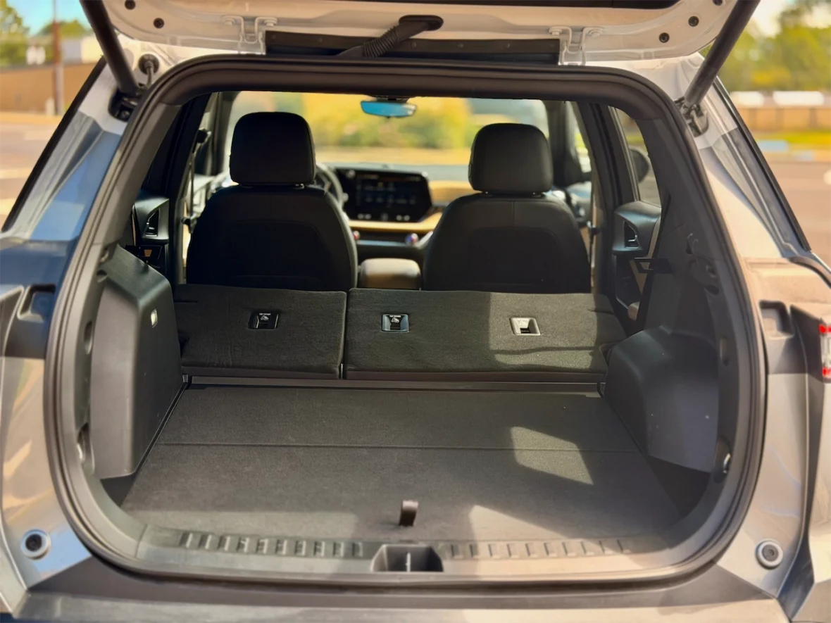 Interior view of a car trunk with seats folded down, featuring a spacious, carpeted area and two front seats visible in the background.