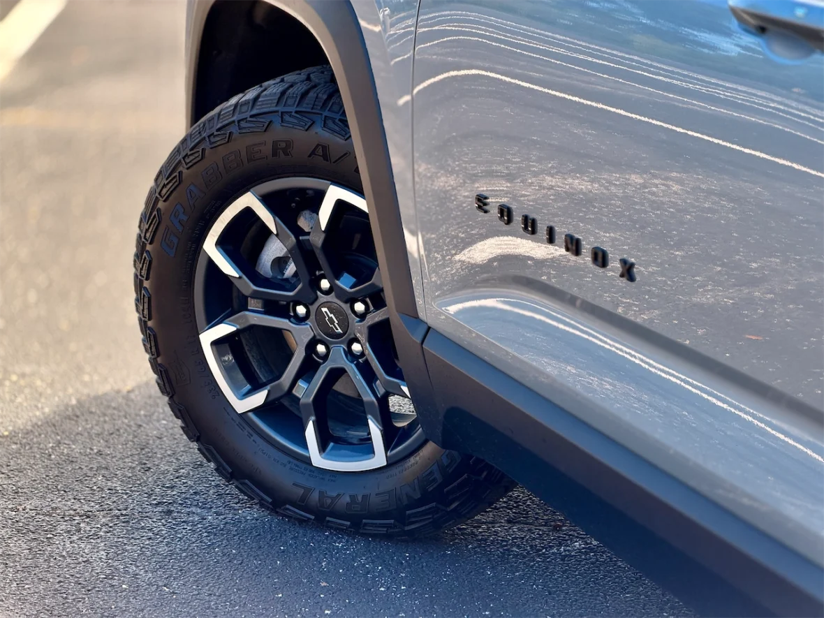 Close-up of the wheel and tire of a Chevrolet Equinox, showcasing a black and silver alloy rim with the 'Grabber A/T' tire.