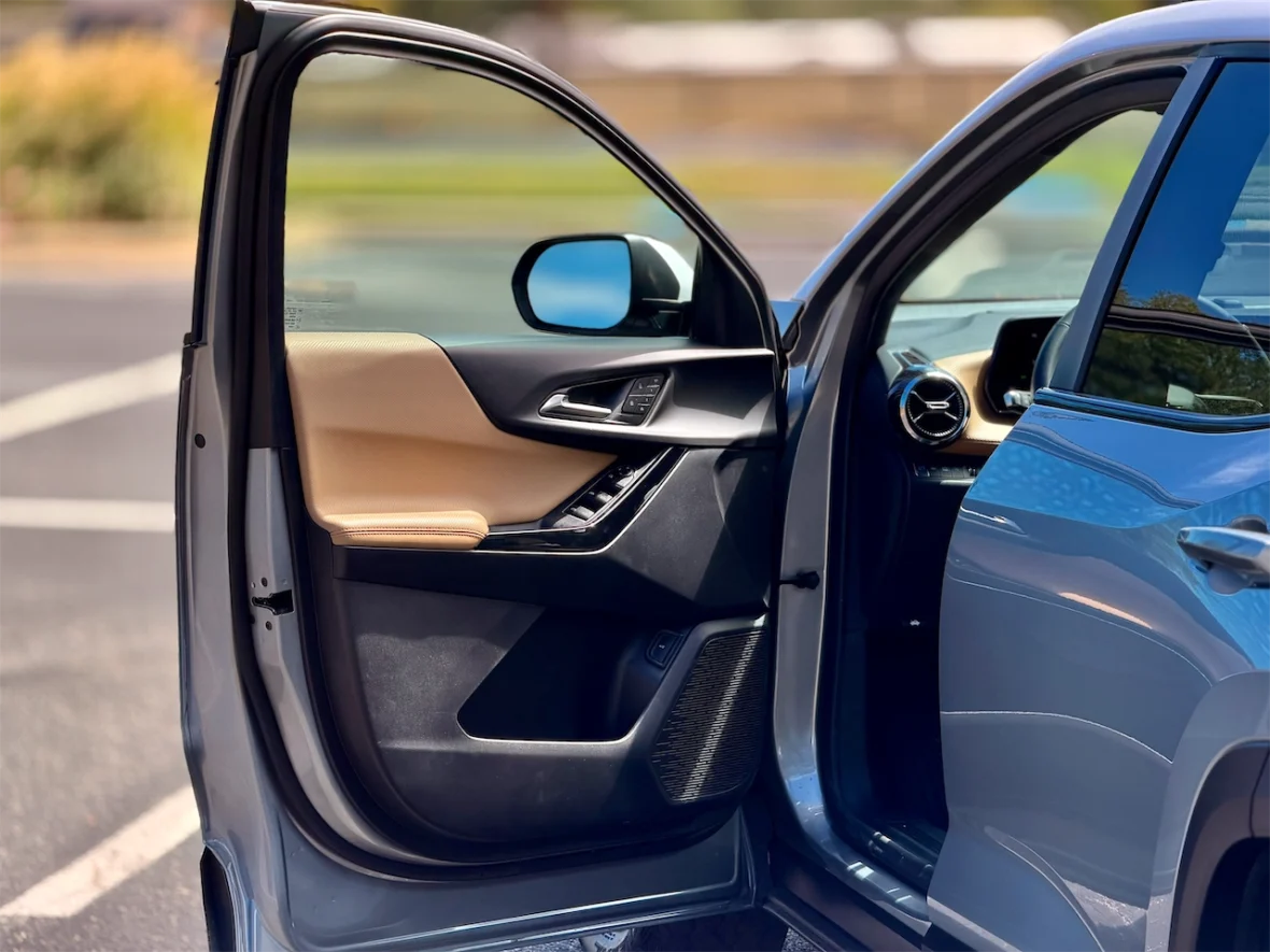 Interior view of a car door opened, showcasing a brown and black door panel, with a glimpse of the dashboard and seats visible in the background.