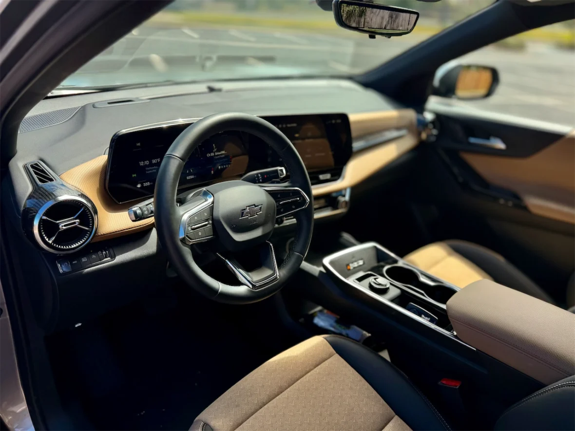 Interior view of a modern Chevrolet car showcasing the dashboard, steering wheel, and seats with a combination of black and beige upholstery.
