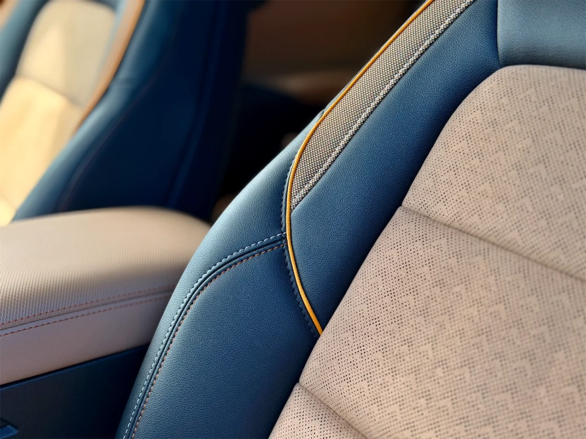 Close-up of car seats featuring a combination of blue and beige leather with textured patterns and contrasting stitching.